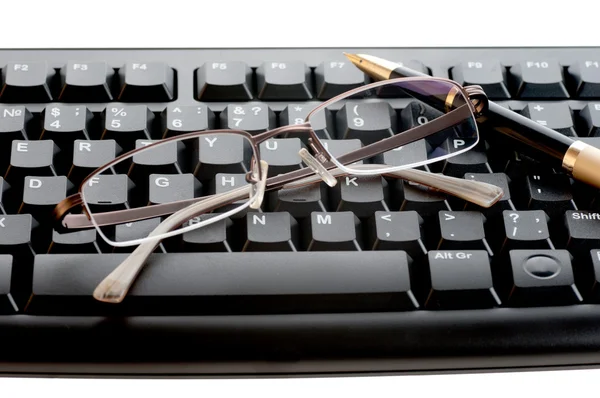 Pen with a golden feather and glasses is on the black keyboard — Stock Photo, Image