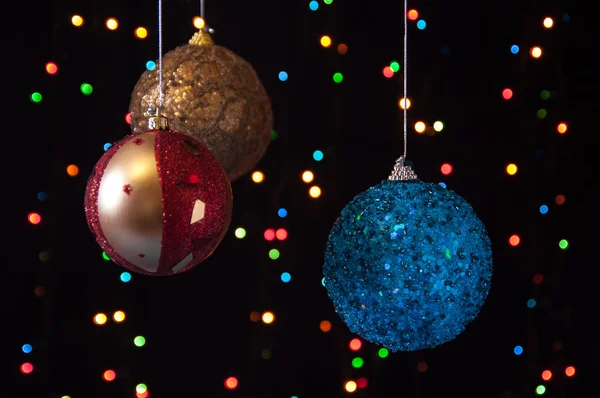 Tres bolas de Navidad sobre un fondo negro con luces — Foto de Stock