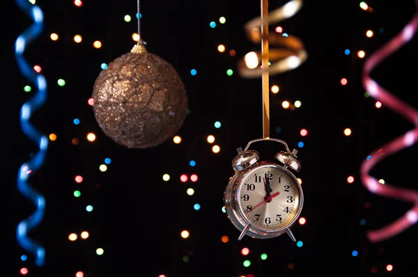 Clock,serpentine,Christmas ball on a black background with lights — Stock Photo, Image