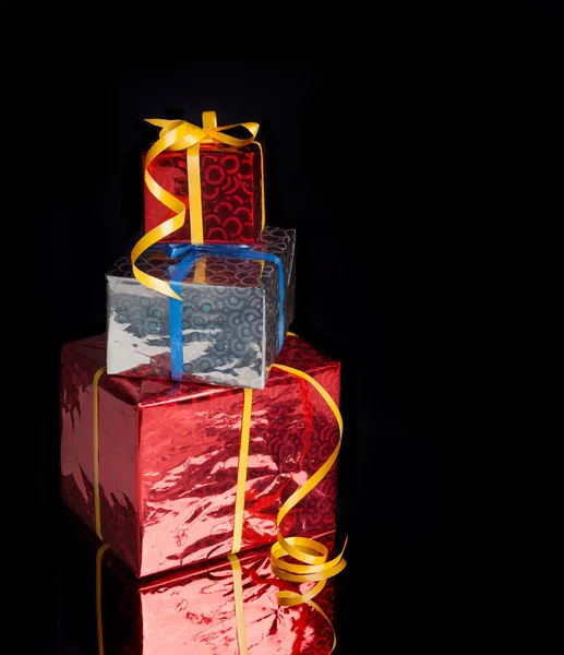 Três presentes em um fundo preto com reflexão — Fotografia de Stock