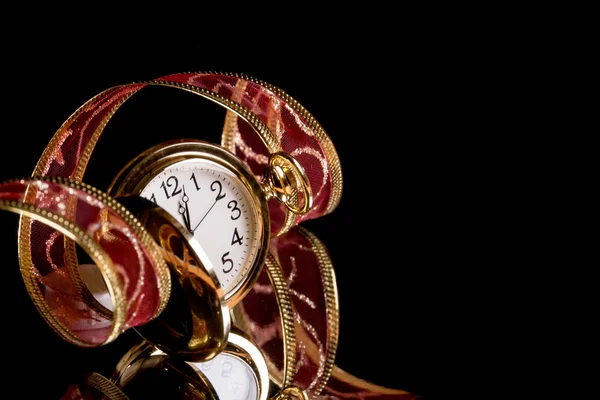 Reloj de oro y una delicada cinta roja sobre un fondo negro — Foto de Stock