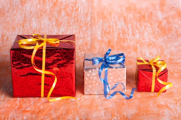 Three gift boxes on an orange background — Stock Photo, Image