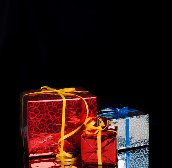 Three gifts on a black background with reflection — Stock Photo, Image