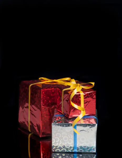 Three gifts on a black background with reflection — Stock Photo, Image