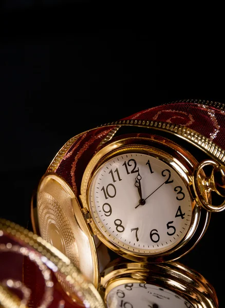 Orologio rotondo in oro con un traforo un nastro rosso su uno sfondo nero — Foto Stock