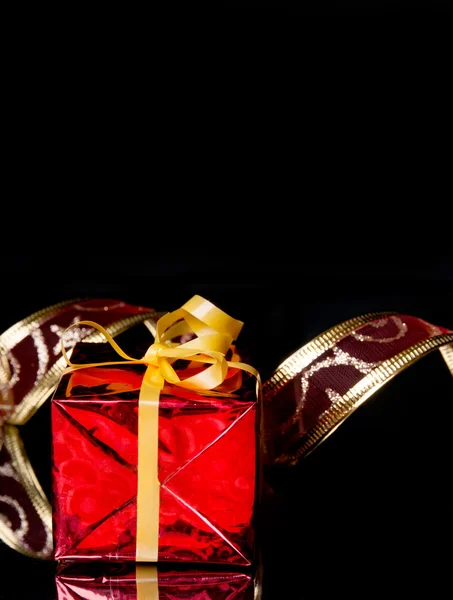 Gift in the red packaging and delicate ribbon on a black background with reflection — Stock Photo, Image