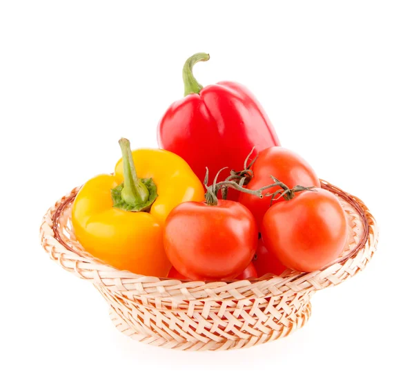 Tomatoes and peppers in a wicker basket on a white background — Stock Photo, Image