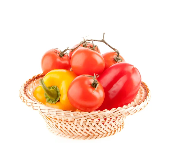 Tomatoes and peppers in a wicker basket on a white background — Stock Photo, Image