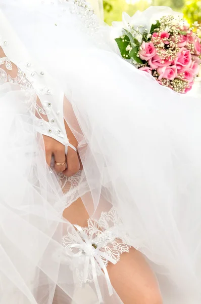 The bride shows the garter on her leg — Stock Photo, Image