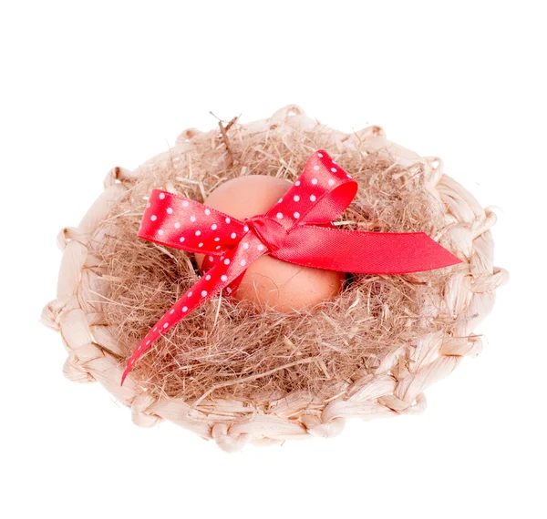 Easter egg with a red ribbon in the straw hat — Stock Photo, Image
