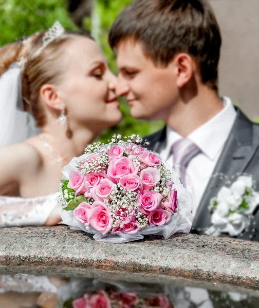 Brud og brudgom kysser i bakgrunnen av en blomsterbukett – stockfoto