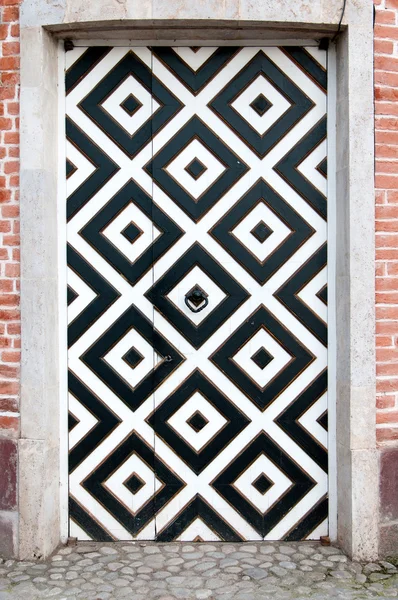 Door into a brick wall with white and black squares ornament — Stock Photo, Image