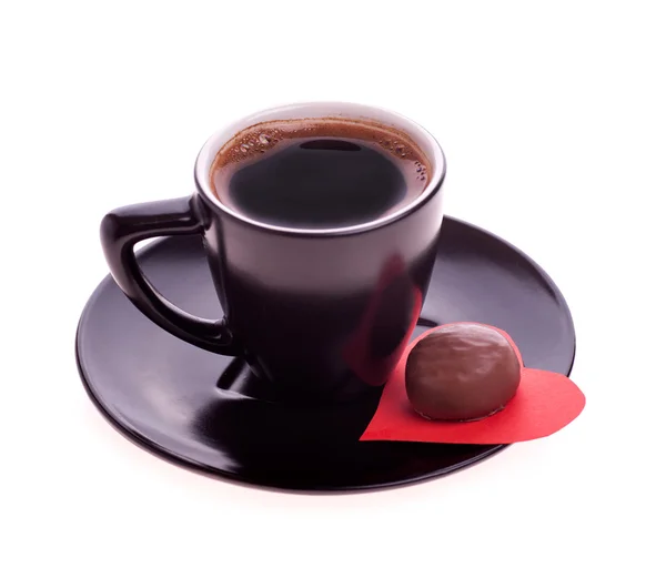 Dulces de chocolate en el corazón del papel y la taza de café negro — Foto de Stock