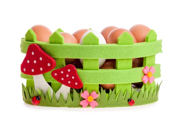 Chicken eggs in the green decorative basket on the white — Stock Photo, Image