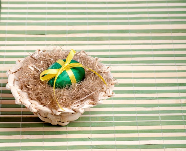 Зелене пасхальне яйце в солом'яному капелюсі на декоративній соломі — стокове фото