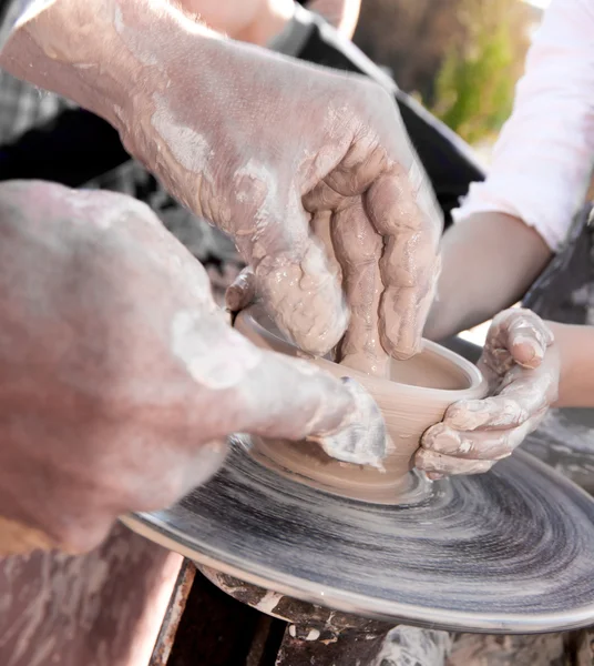 Hand of the potter and the child in the creation of new products — Stock Photo, Image