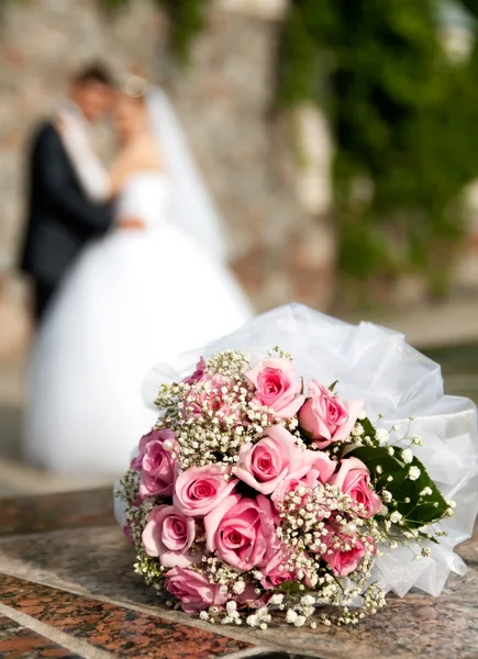 Boeket rozen ligt op de achtergrond van de bruidegom en de bruid — Stockfoto