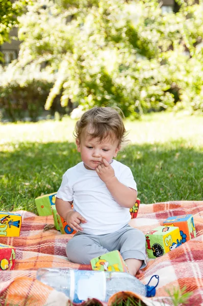 Маленький ребенок сидит среди игрушек — стоковое фото