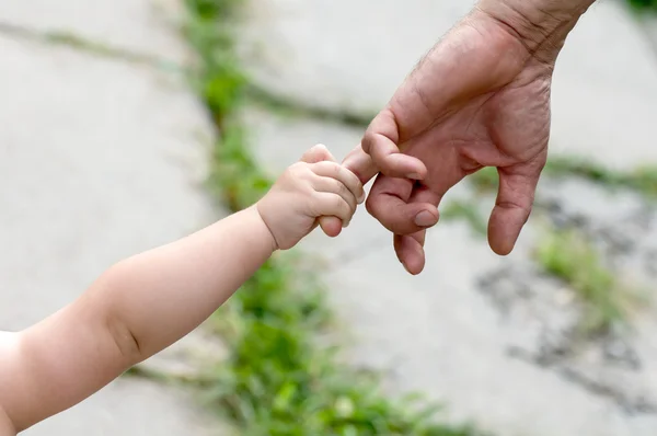 Criança segura o dedo de uma mão do pai — Fotografia de Stock