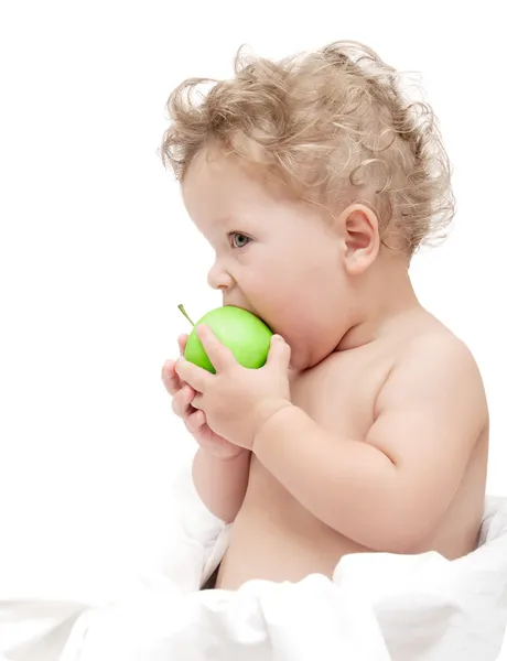 Portrait of a child curly hair eats a green apple — Stock Photo, Image