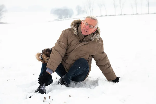 Senior mit verletztem Bein auf Schnee lizenzfreie Stockbilder