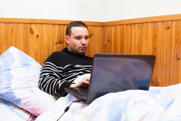 Man med laptop i sängen — Stockfoto