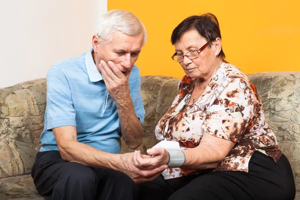 Занепокоєні літні люди, що вимірюють кров'яний тиск — стокове фото