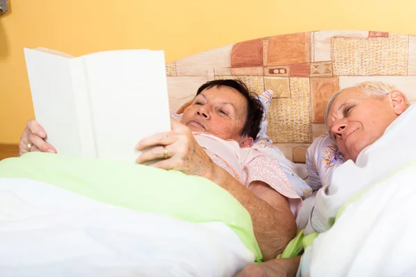 Anziani lettura libro a letto — Foto Stock