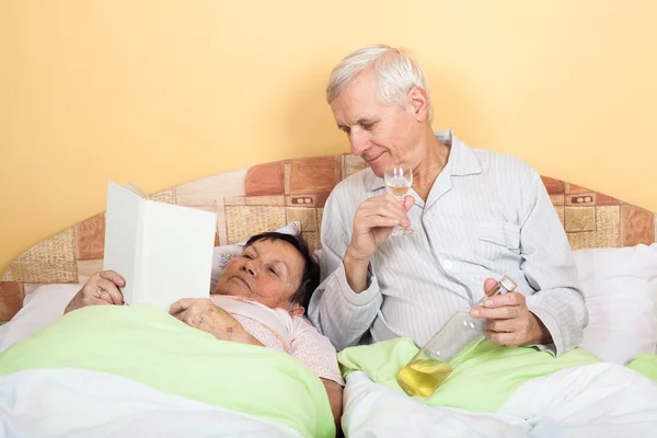 Grappige senioren ontspannen met alcohol in bed — Stockfoto