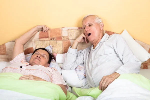 Sleepy senior couple yawning in bed — Stock Photo, Image