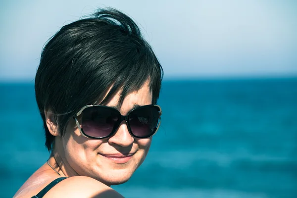 Woman in sunglasses over blue sea and sky — Stock Photo, Image