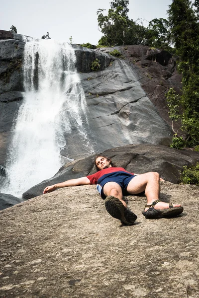 Man relaxing next to waterfall — Stock Photo, Image