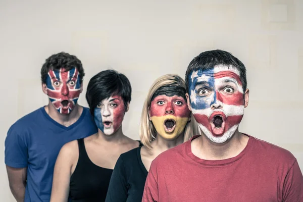 Personas sorprendidas con banderas en los rostros —  Fotos de Stock