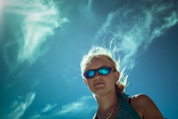 Femme souriante dans des lunettes de soleil de sport sur le ciel bleu — Photo