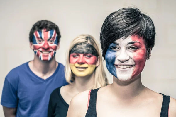 Happy people with painted flags on faces — Stock Photo, Image
