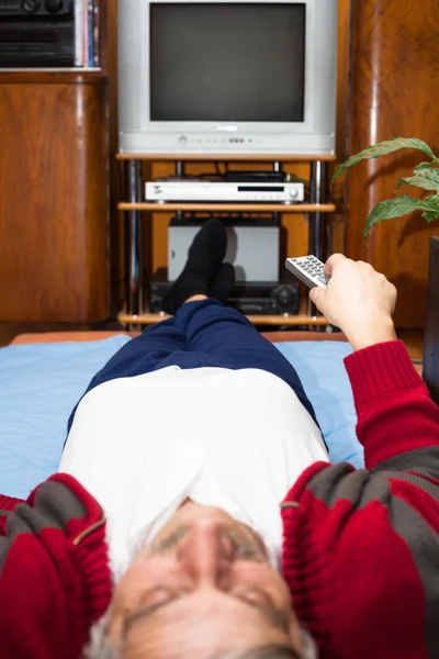 Idoso com controle remoto assistindo TV — Fotografia de Stock