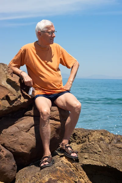 Senior tourist man on the rocky beach — Stock Photo, Image