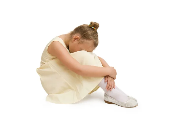 Retrato de una niña infeliz sentada en el suelo. Aislado sobre blanco —  Fotos de Stock