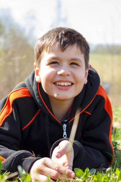 Portrait en gros plan d'un garçon rieur allongé sur l'herbe — Photo