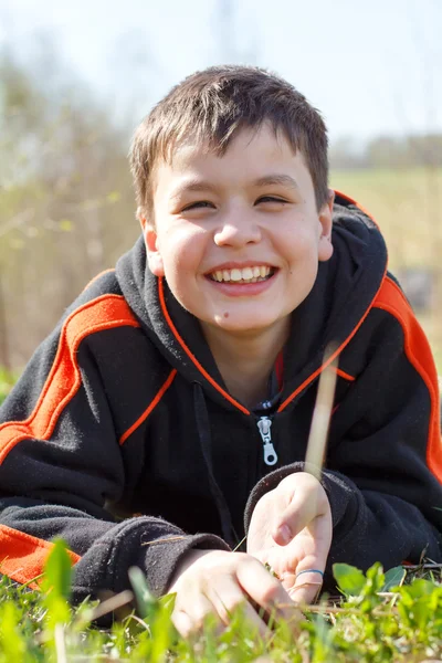 Close-up portrait of laughing boy lying on the grass — Stock Photo, Image