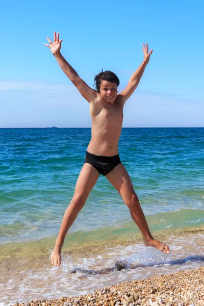 Lycklig pojke hoppar på stranden — Stockfoto