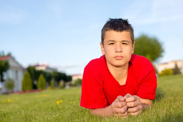 Serious teenage summer lies in the grass — Stock Photo, Image
