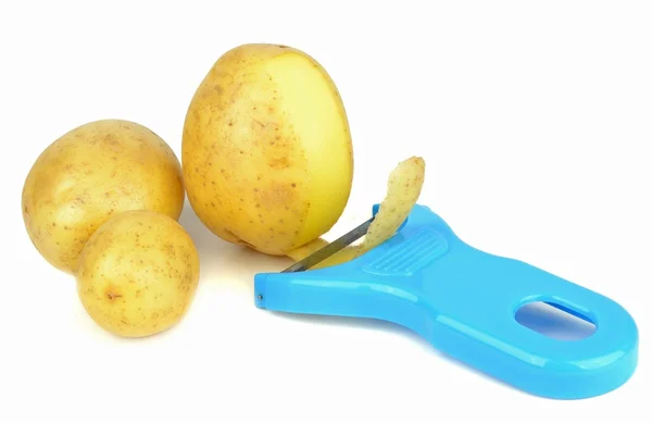 Potato peeler and potatoes — Stock Photo, Image