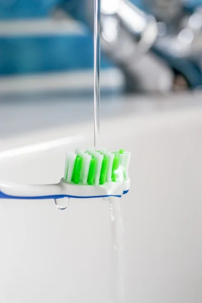 Uma escova de dentes sob água corrente da torneira — Fotografia de Stock