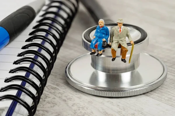 Conceptual Image Elderly Health Care Miniature Couple Sitting Doctor Stethoscope — Photo