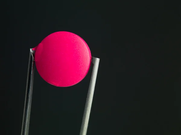 Pink pill in tweezers — Zdjęcie stockowe