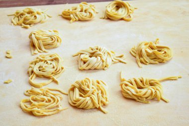 Ev yapımı yumurta tagliatelle, ahşap bir pasta tahtasında.