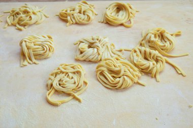 Ev yapımı yumurta tagliatelle, ahşap bir pasta tahtasında.