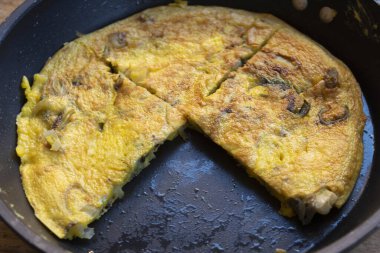 Yumurtalı frittata üç parçaya bölünmüş ve tavada pişirilmiş.