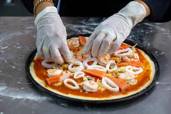 The process of making pizza seafood with squid and shrimp, close up.Italian chef cook homemade delicious pizza with wood fired oven.